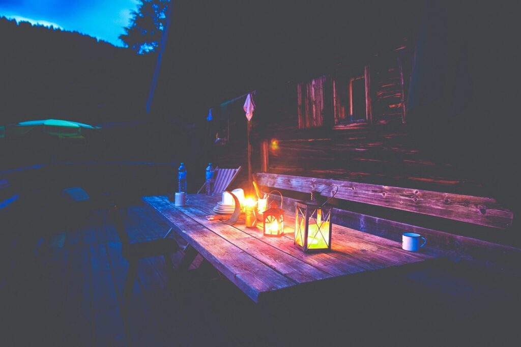 lit lanterns on a picnic table at night