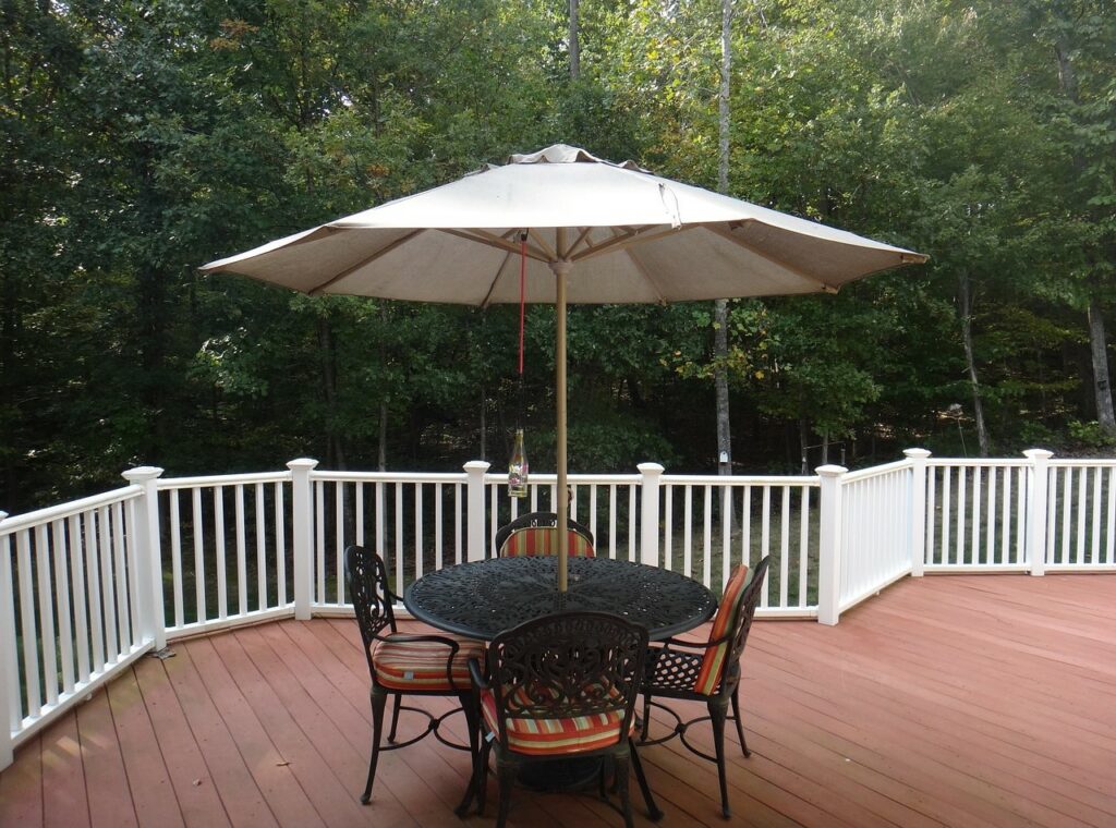 small table and chairs on an outdoor deck with open umbrella