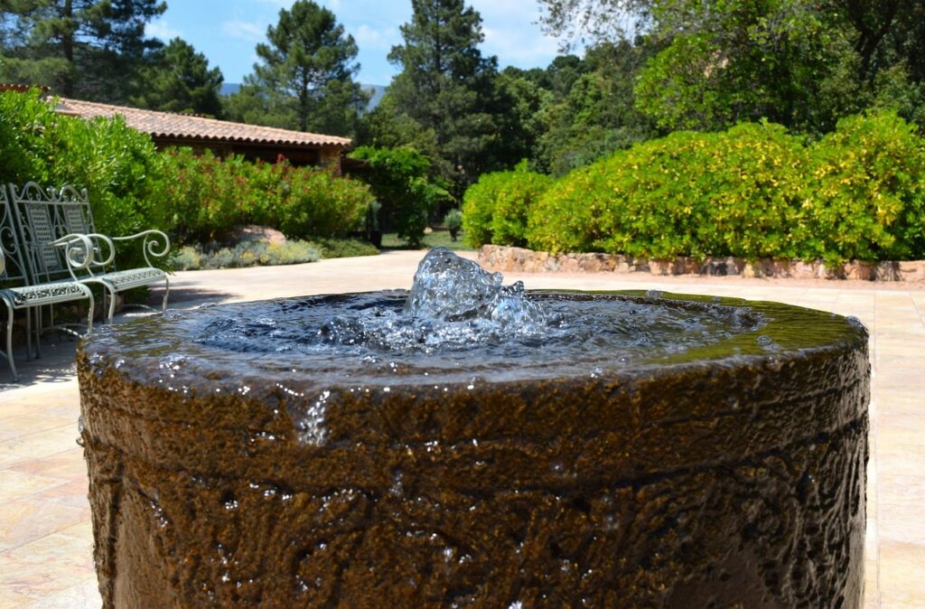 Bubbling water fountain on a tiled outdoor patio with chairs